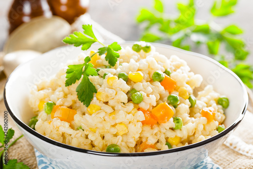 Bulgur wheat boiled with carrot, green peas and corn, healthy vegan diet
