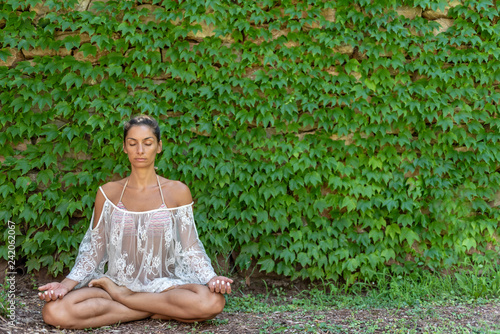Obraz na plátne Beautiful, peaceful woman dressed in white romantic blouse practicing yoga in nature