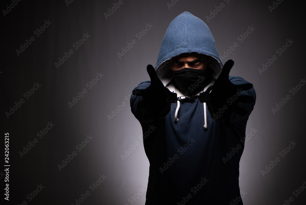 Young gangster in hood on grey background Young gangster in hood on grey background