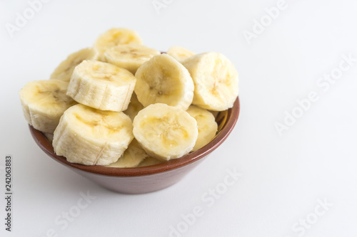 Bowl with banana slices on white background