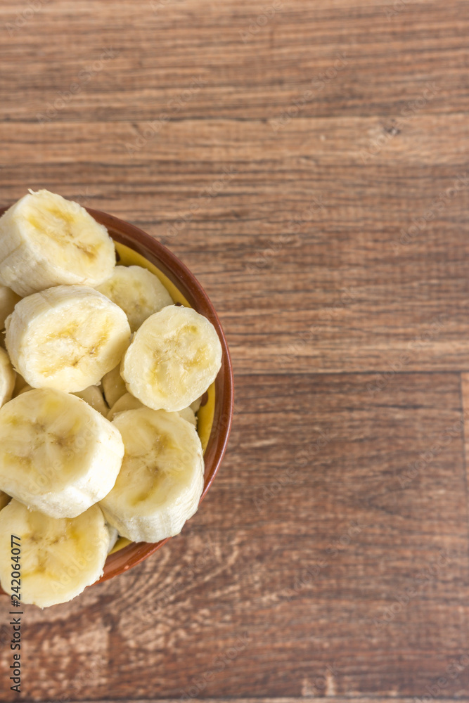 Bowl with banana slices on wooden background Bowl with banana slices on wooden background