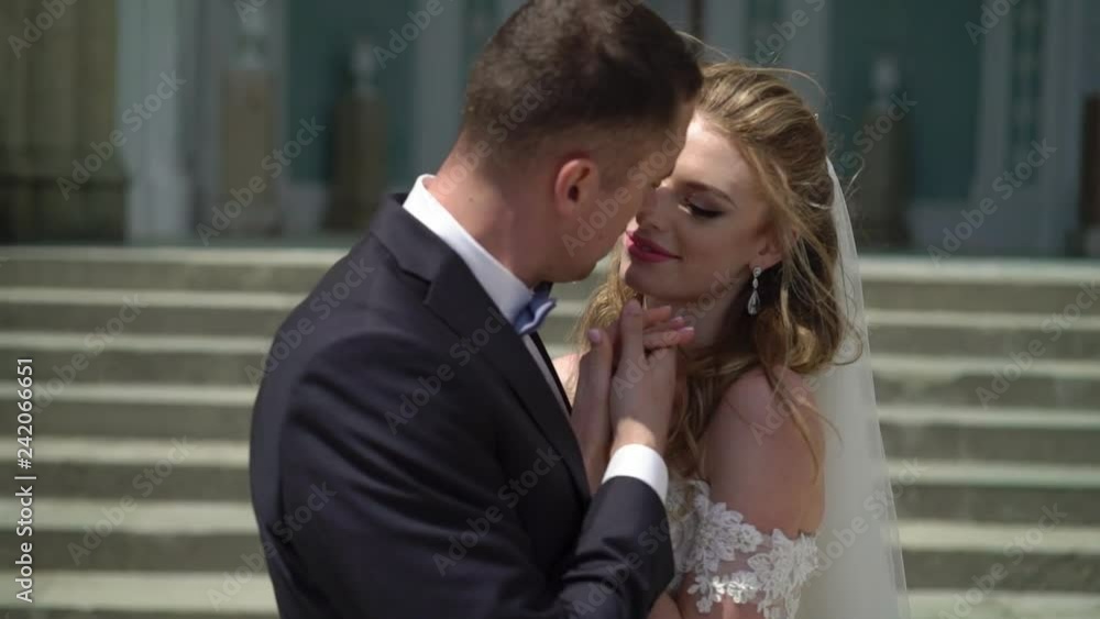 Young bride and groom posing in a city. Waving veil at windy summer day. Slowmotion Young bride and groom posing in a city. Waving veil at windy summer day. Slowmotion