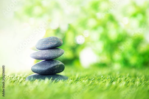 balance with a pyramid of stone on fresh nature green grass , spa meditation or well-being with zen concept