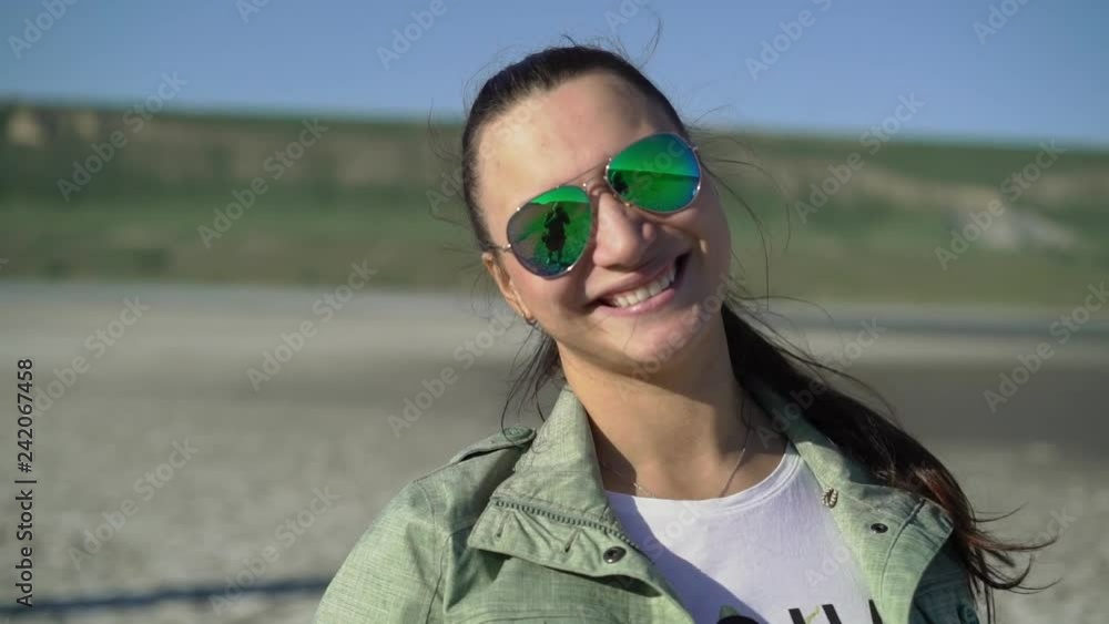 Young woman in green sunglasses smiling outdoors at nature Young woman in green sunglasses smiling outdoors at nature
