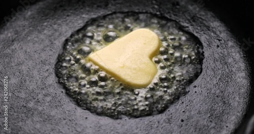 Fried butter, a piece of butter in the shape of hearts, fried on a black cast-iron pan. Impression about a healthy heart, anti cholesterol prophylaxis, healthy heart concept, 4k photo