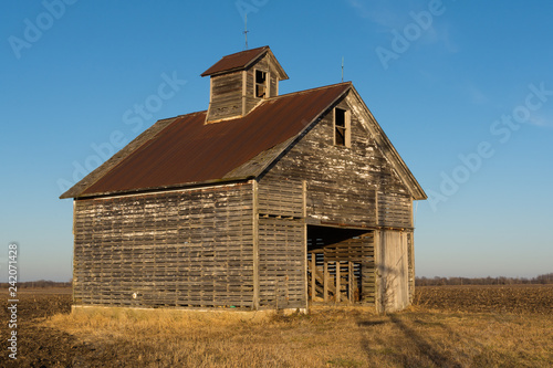 Old weathered wooden barn in open field on a Winter afternoon. LaSalle County, Illinois, USA