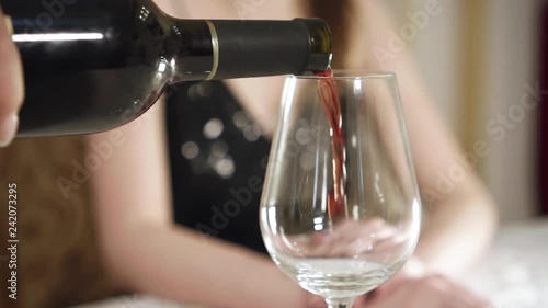 Waiter pouring red wine into glass. Close-up. Slow motion.