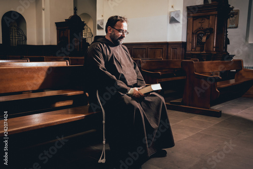 Fotótapéta A monk in robes with holy bible in their hands praying in the church