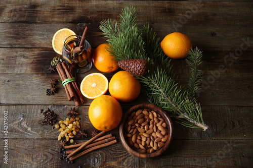 christmas still life with nuts, oranges and spices on a wooden background with a spruce branch