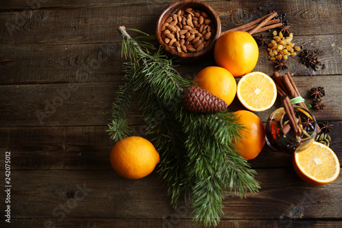 christmas still life with oranges, almonds, and cinnamon on a wooden background, with a spruce branch with space for text