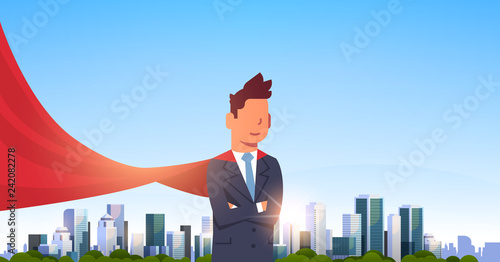 businessman wearing red super hero cape representing business power and courage leadership success concept over big modern city skyscraper cityscape skyline flat horizontal