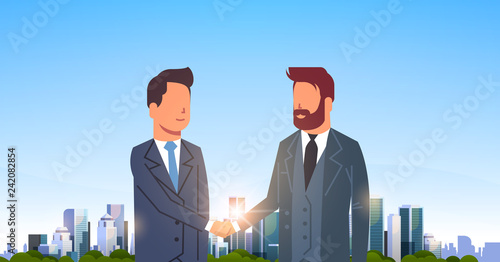 two businessmen shaking hands partners successful agreement business deal hand shake concept over big modern city building skyscraper cityscape skyline flat horizontal