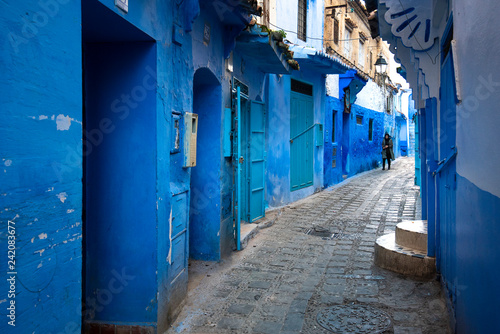 Beautiful view of the blue city in the medina. Traditional moroccan architectural details and painted houses.  street with door and bright blue walls with arch in CHEFCHAOUEN, MOROCCO © mitzo_bs