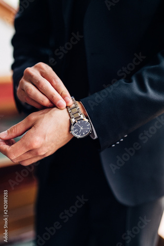 man in business suit putting on watch