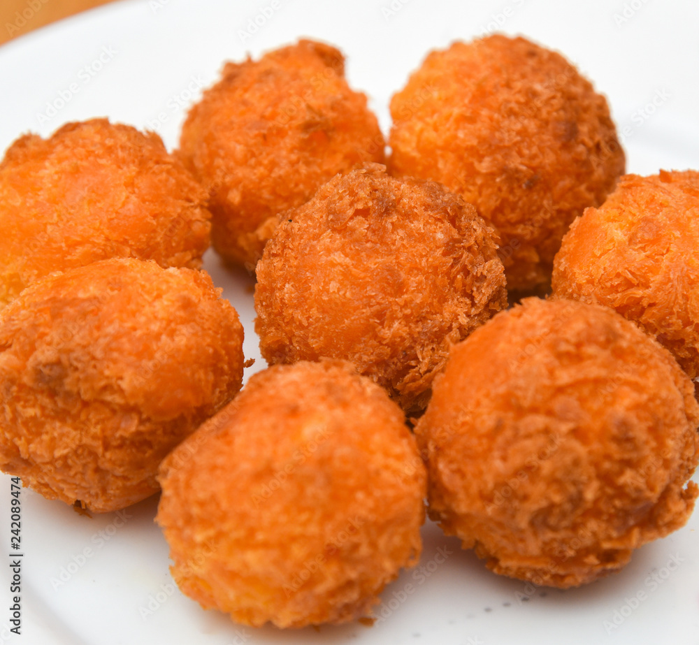 Cheese balls, Breaded mozzarella cheese balls with tomato in white dish on wood blackground Cheese balls, Breaded mozzarella cheese balls with tomato in white dish on wood blackground