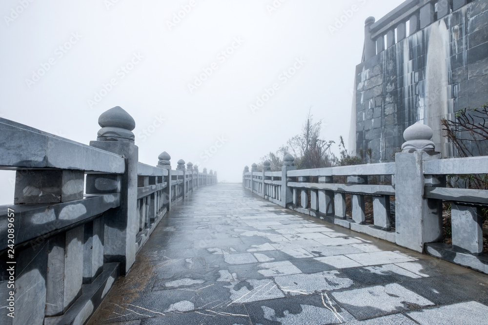 Obraz premium Stone rail and walkway with misty on hill