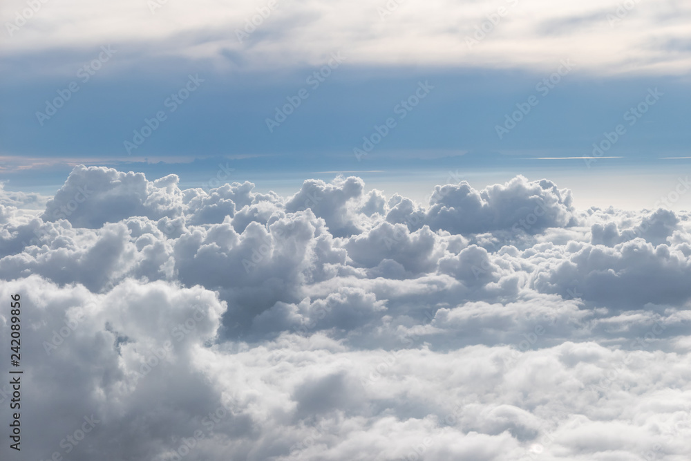 Fototapeta premium Above fluffy clouds with blue sky from airplane
