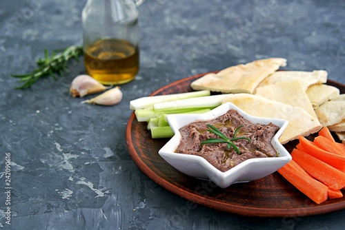 Red bean dip with baked garlic, thyme and olive oil in a star bowl. Served with chopped raw carrots, celery and pita pieces.