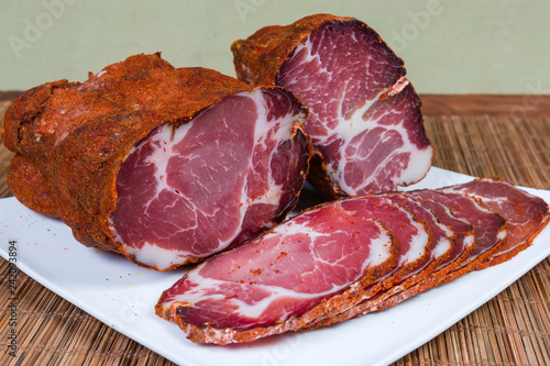 Partly sliced dried pork neck on dish close-up photo