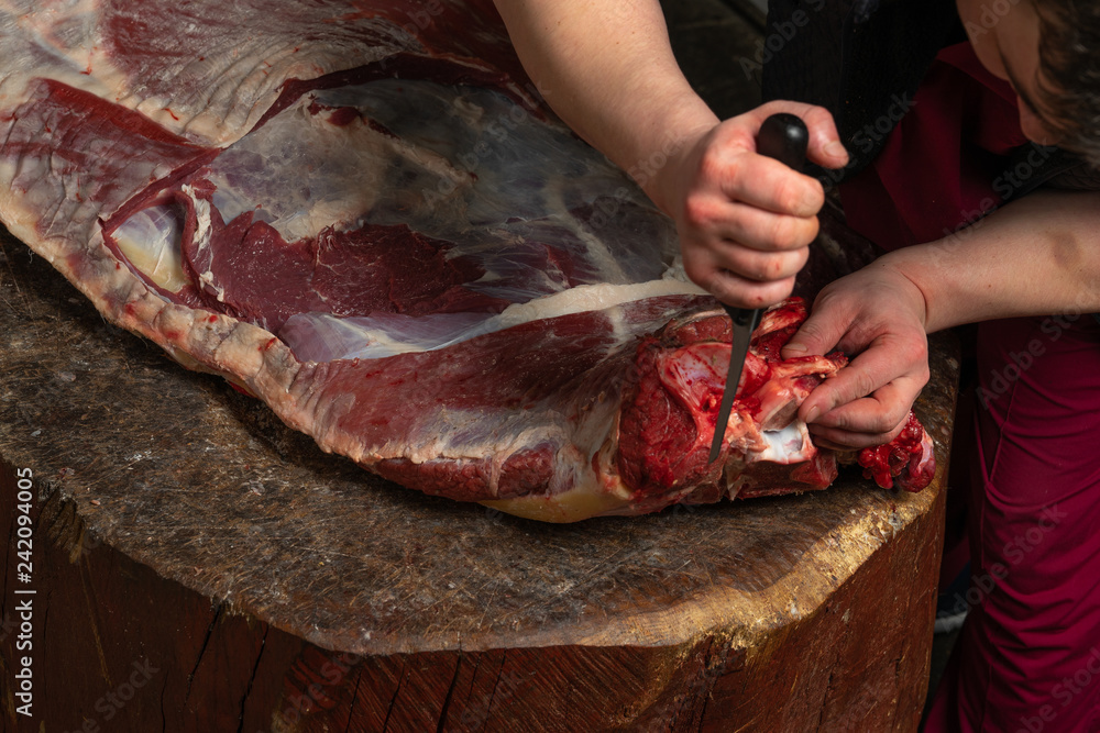 a butcher chopping a large carcass of beef