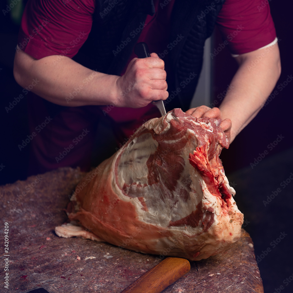 Close-up of the hands of a butcher cutting slices of raw lamb