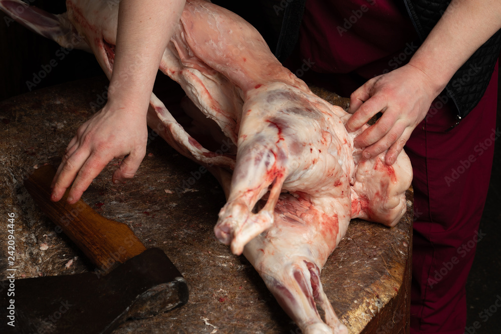 Butcher chopping lamb with an axe on the chopping board