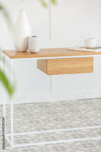 Stylish industrial console table with vases and coffee mug on magazine