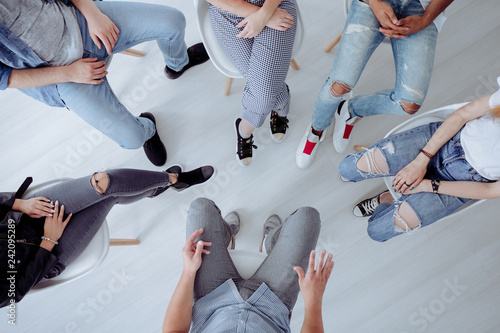 Tablou pe pânză Top view of troublesome teenagers and their therapist during professional talk w