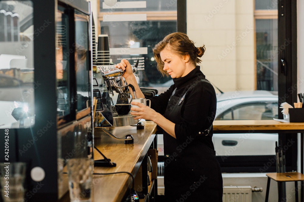 Young owner female barista in black uniform working with coffee machine  pouring milk cappuccino in modern coffee shop. Side view. Stock Photo |  Adobe Stock