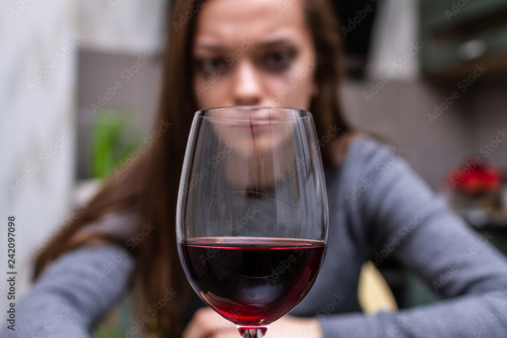 Depressed, divorced crying woman sitting alone in kitchen at home and drinking a glass of red wine because of problems at work and troubles in relationships. Social and life problems Depressed, divorced crying woman sitting alone in kitchen at home and drinking a glass of red wine because of problems at work and troubles in relationships. Social and life problems