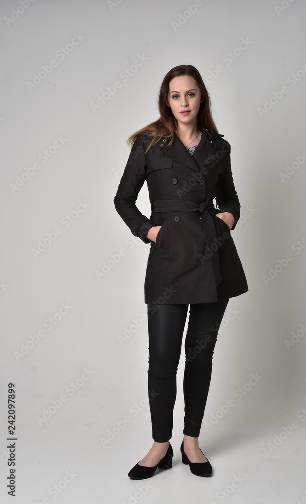 full length portrait of a brunette girl wearing long black coat, standing pose on grey studio background. full length portrait of a brunette girl wearing long black coat, standing pose on grey studio background.