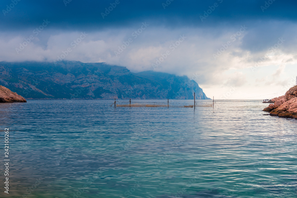 Gloomy dramatic rain clouds over the calm sea and mountains, picturesque landscape