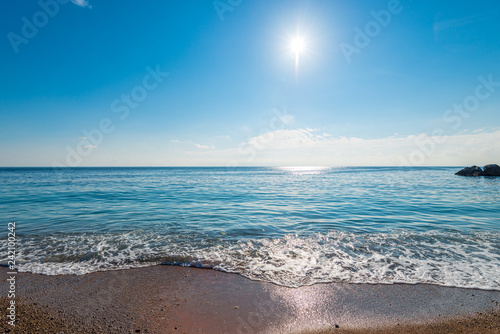 calm blue sea water and bright sun above the horizon