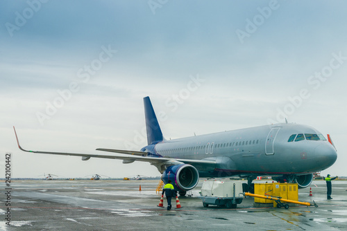 The plane in the parking lot at the airport, airport workers in the frame