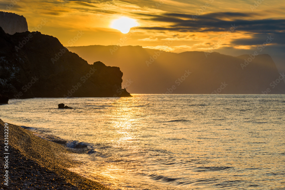The Black Sea in the rays of the rising sun, a view of the water and rocks. Orange Tone's Photo