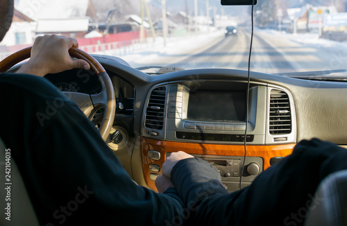 touch of hands of the man and the woman, against controls, the monitor, the panel of the car and the carriageway covered with snow in the settlement behind a window