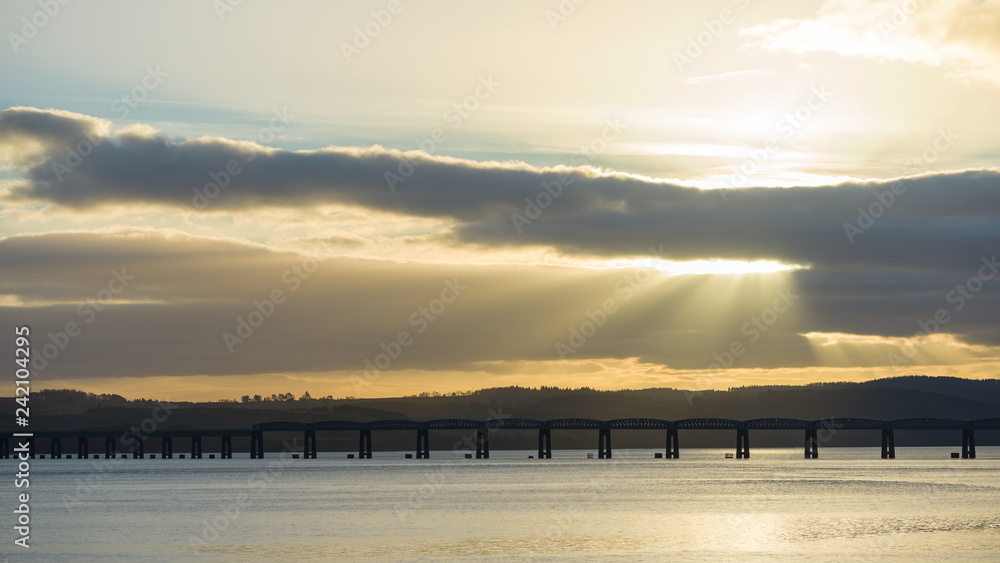 Fototapeta premium Old railroad bridge at sunset/sunrise, rays of sunlight leading way through clouds
