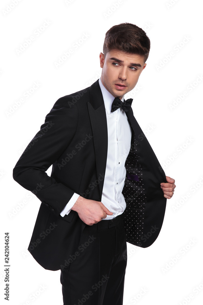 attractive businessman holding black suit collar and looking to side attractive businessman holding black suit collar and looking to side