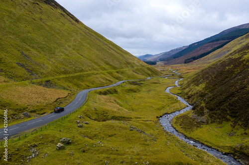 SUV on windy road in green volcanic mountains of Scottish highlands