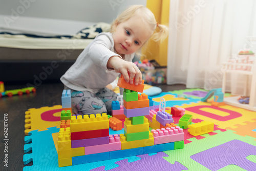 little girl playing with building blocks on the floor at home