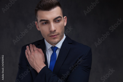 portrait of curious businessman in navy suit touching his chest