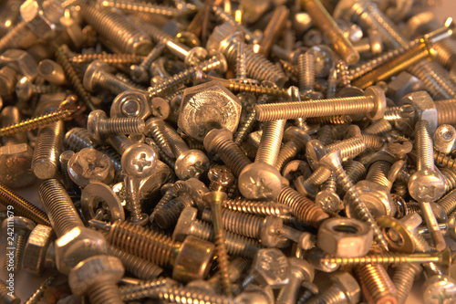 Screw and bolts pile on yellow incadescent background photo