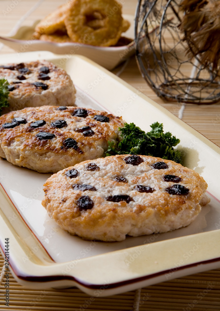 Close-up of row of three turkey burgers with cooked raisins with blurred background Close-up of row of three turkey burgers with cooked raisins with blurred background