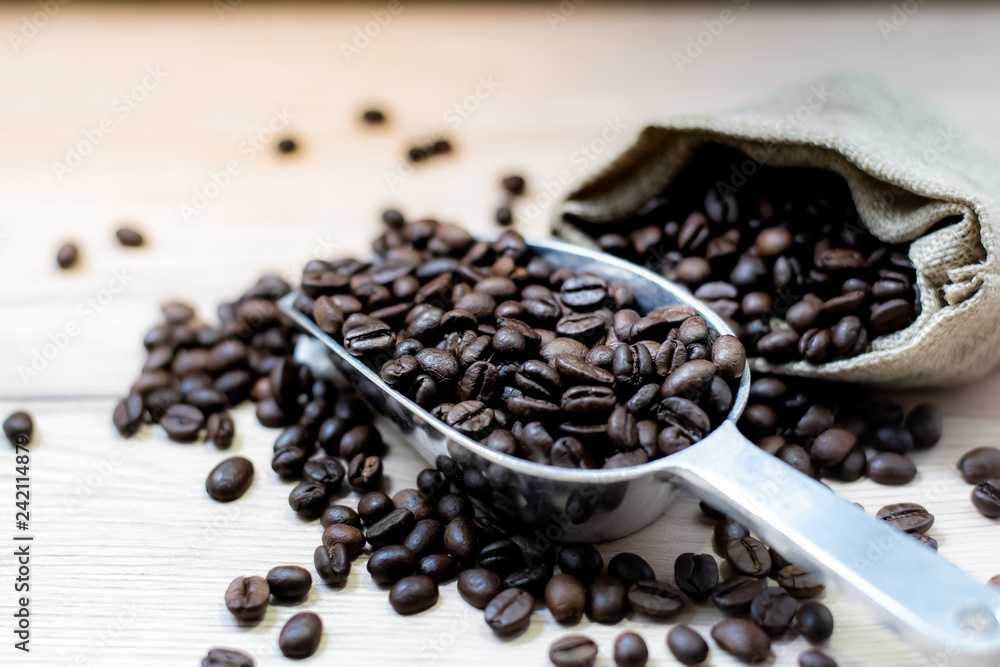 Coffee beans are placed in containers and spread on the background of wood grain. Coffee beans are placed in containers and spread on the background of wood grain.