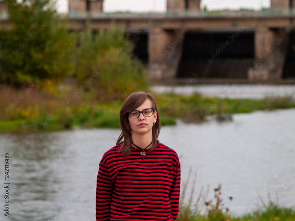 Portrait of a teenage girl gesturing and smiling on the shore of a river Portrait of a teenage girl gesturing and smiling on the shore of a river