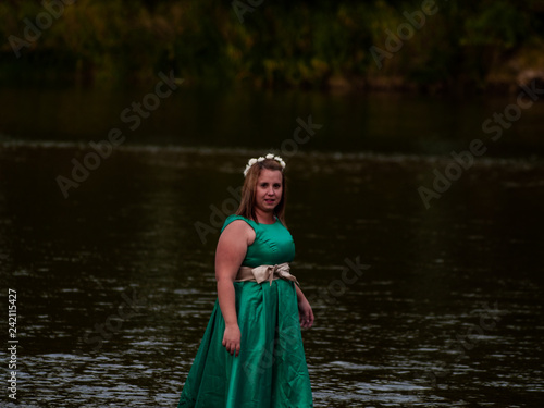 Fototapeta Naklejka Na Ścianę i Meble -  Portrait of a cheerful young woman in a river dressed with a green party dress