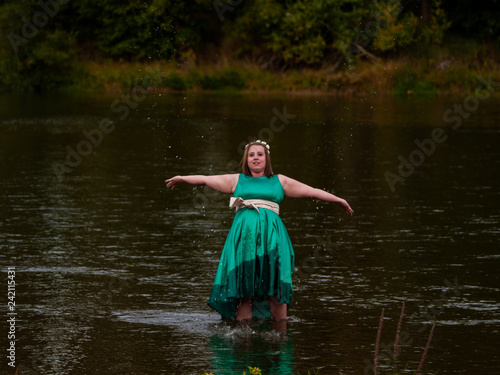 Fototapeta Naklejka Na Ścianę i Meble -  Portrait of a cheerful young woman in a river dressed with a green party dress