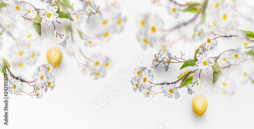 Tableau sur toile Hanging yellow Easter eggs and spring blossom branches at white wall background, banner