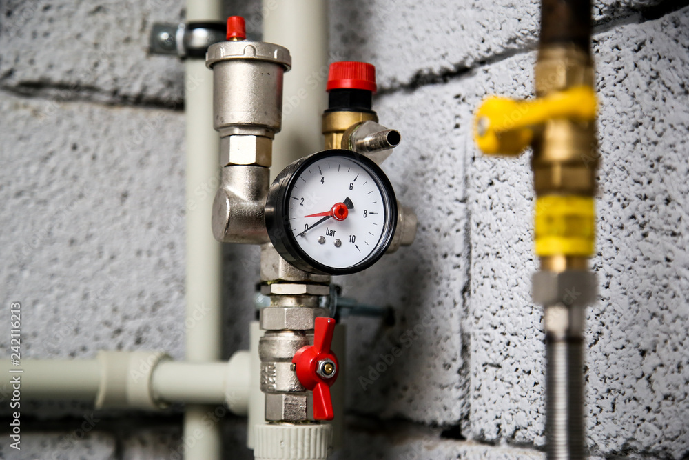 Closeup of manometer, pipes and faucet valves of heating system in a boiler room at home Closeup of manometer, pipes and faucet valves of heating system in a boiler room at home