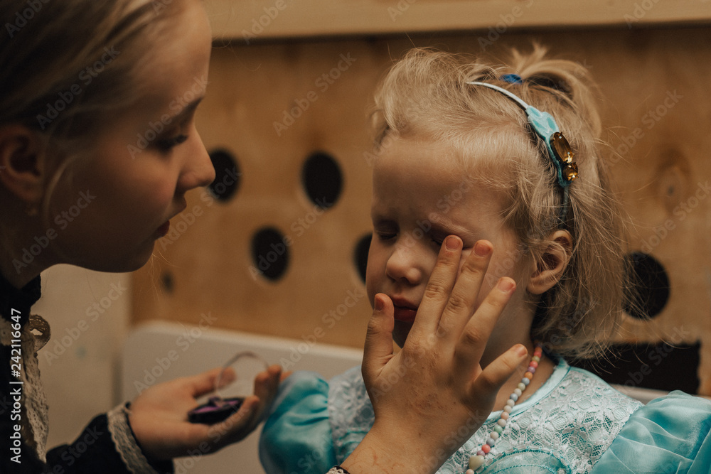Fototapeta premium nastolatka maluje swoją młodszą siostrę makijażem